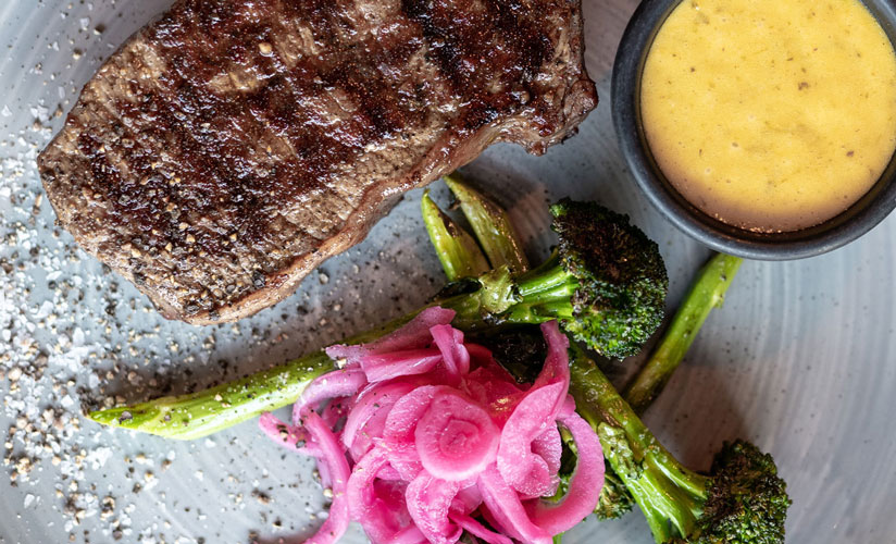 Entrecôte, brokkolini, rødløk ceviche og bearnaisesaus på en tallerken