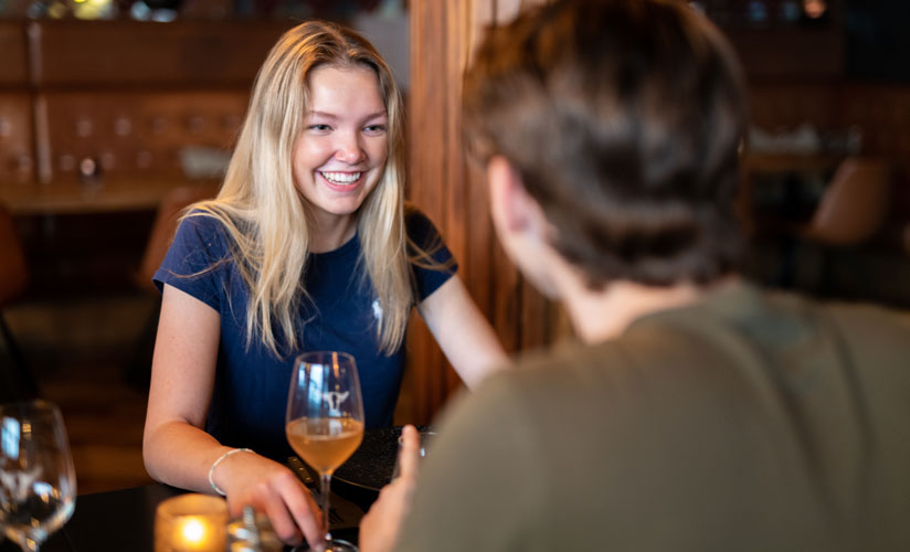 Jente smiler til gutt. Ungt par som spiser på restaurant hos Big Horn Steakhouse