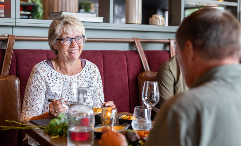 Smilende dame spiser middag på restaurant hos Big Horn Steakhouse